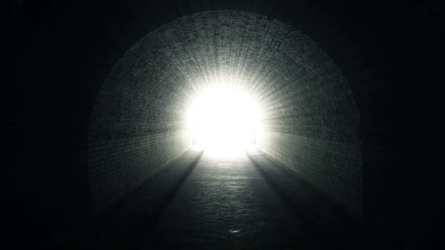 Dark brick tunnel interior facing a blinding bright exit as light rays stream inward and shadows stretch along the floor, creating a dramatic passage scene
