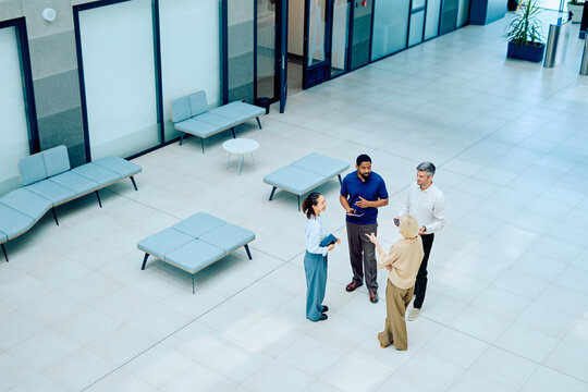 Business team interacting, discussing project, and networking in a spacious company reception area during a casual meeting