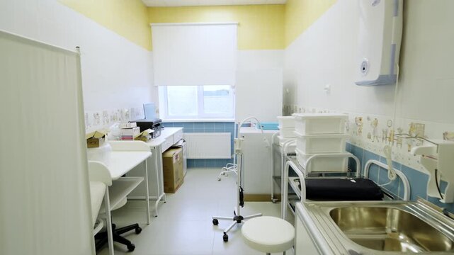 Examination room in clinic includes desks hygienic washbasins examination couch for patients. Bright lighting creates welcoming atmosphere