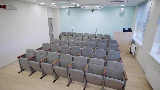 Meeting room includes gray upholstered chairs high-quality microphones on sturdy stands. Furnishings designed for conferences and seminars