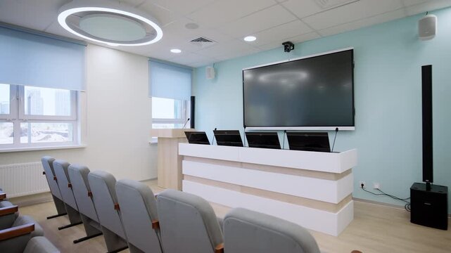 Conference hall contains comfortable gray upholstered chairs modern television. Well-equipped presentation spaces for lecturers and guests