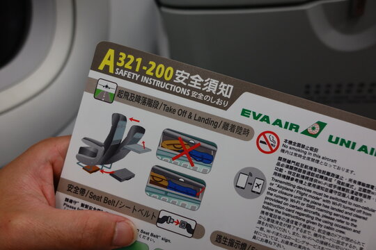 Passenger holding an aircraft safety instruction card in the cabin.