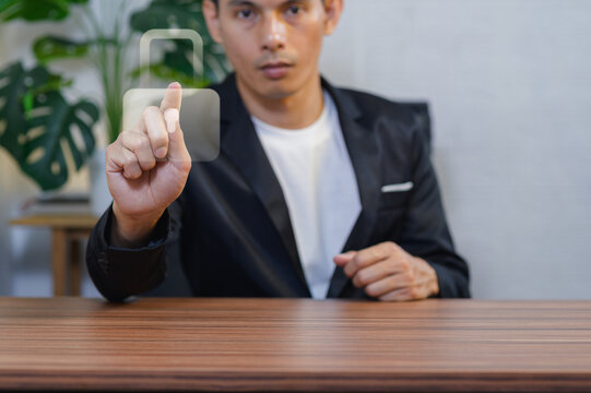 Businessman in formal attire pointing at transparent digital interface in office setting