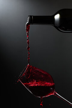 Red wine of rich color being poured from a bottle into a glass.