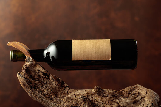 Bottle of red wine with empty label on a old wooden snag.