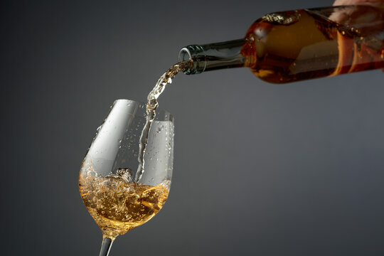 Pouring white wine from a bottle into a glass.