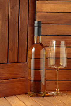 Bottle and glass of white wine on a wooden background.