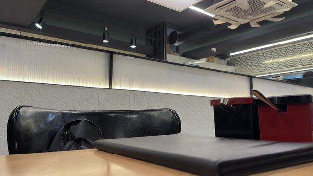 Empty tables and black leather booths inside a modern retro cafe and restaurant interior during vacation