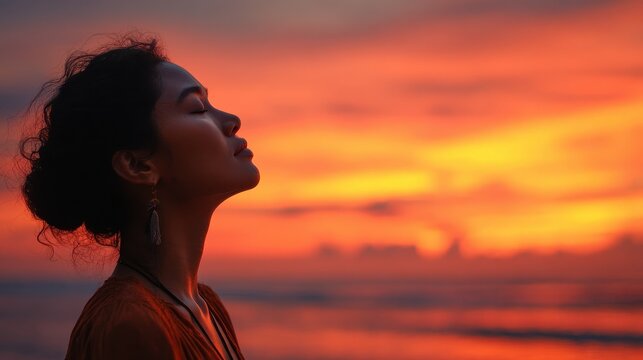 Woman enjoying vibrant sunset at the beach while capturing a moment in quiet reflection surrounded by colors of dusk