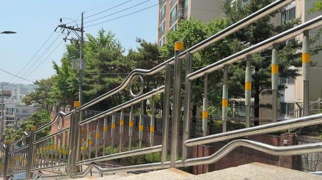 Shiny stainless steel safety railing along a bright residential street with green trees in summer
