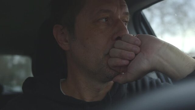 Unhappy male driver resting with hand on face inside vehicle, contemplative mood and everyday exhaustion concept, 4K