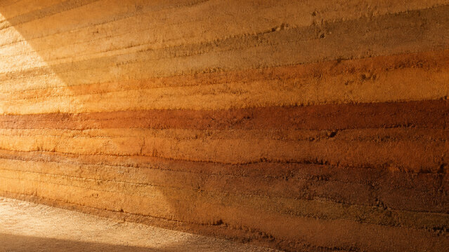 Rough rammed earth wall strata in ochre natural layered texture background