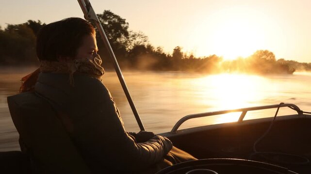 adult woman traveling on speedy boat  at sunrise on the mighty Zambezi River, Zimbabwe, Africa...mist rising on water