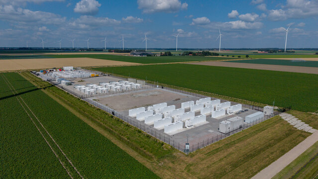 Aerial view of the Olsterdwarspad battery energy storage system with rows of white containers and wind turbines, Dronten, Flevoland, The Netherlands