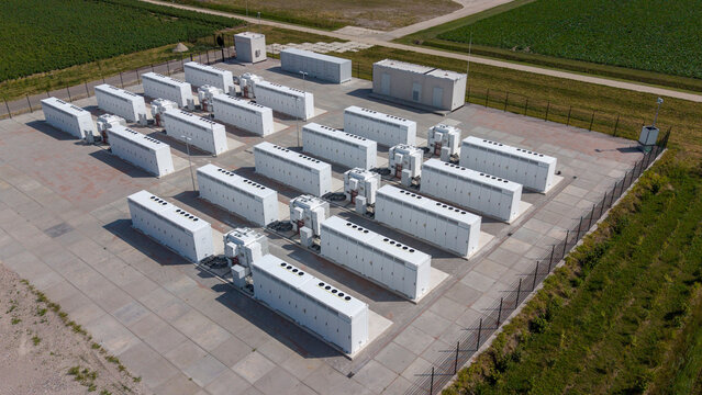 Aerial view of the Olsterdwarspad battery energy storage system with rows of white containers and wind turbines, Dronten, Flevoland, The Netherlands