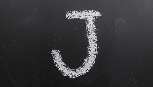暗いスレート黒板に、質感のある白いチョークで手描きされたイニシャルJ