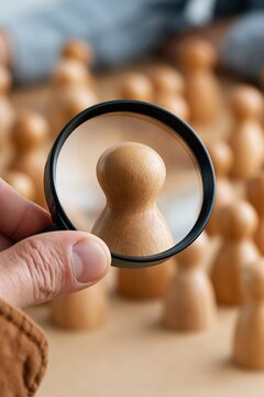 Close perspective of a magnifying lens highlighting a wooden pawn candidate for talent selection and decision making concept background for corporate use