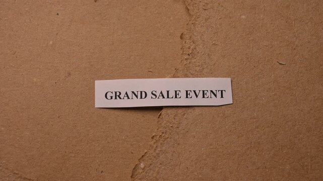 rand Sale Event Message on Paper Note Placed by Hand on Torn Brown Card Background