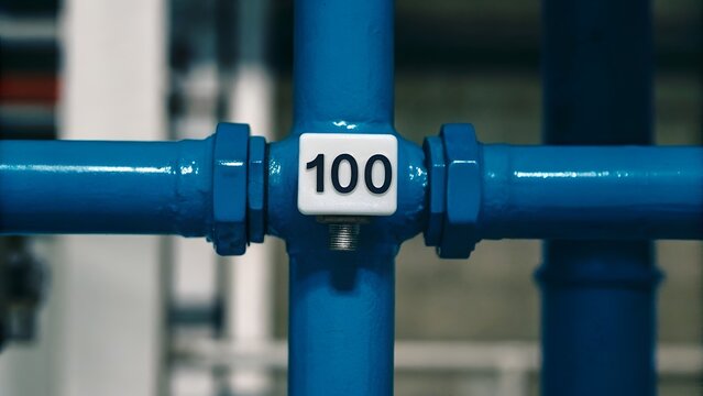 Blue industrial pipe with white and black thermometer displaying 100 degrees, ideal for engineering and temperature monitoring concepts