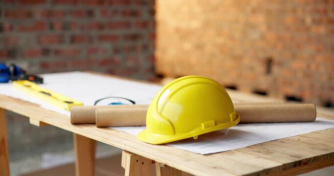 Architecture, helmet and blueprint at empty site for building, maintenance or property development. Hard hat, floor plan and equipment with PPE on desk by construction design for repair or renovation