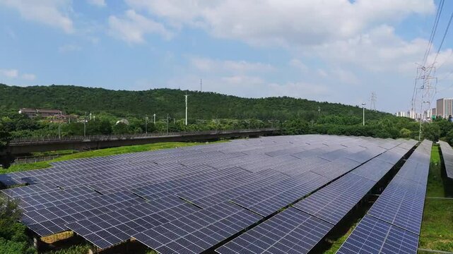 Aerial view of solar panels beside railway and green hills