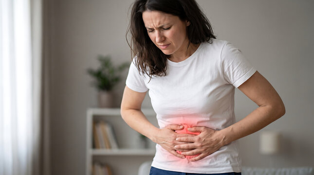 Young woman suffering from severe abdominal pain and stomach ache at home with red highlight
