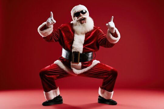 Full length photo of handsome old dabber fat funny santa claus in eyeglasses dance with his hand raised in a funny pose, isolated over red background