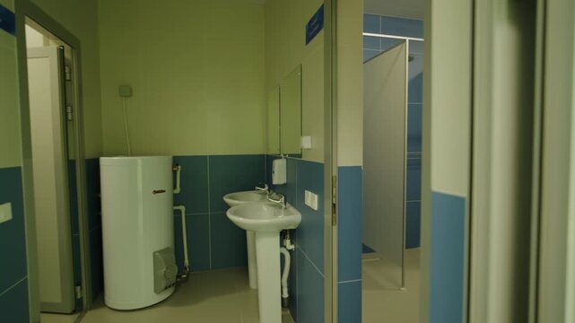Open doorway reveals public restroom equipped with boiler and ceramic sinks. Modern utility space features contrasting wall tiling