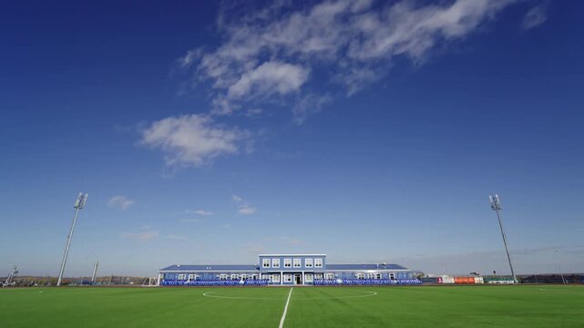Sky with scattered light cirrus clouds spans wide above stadium. Daytime view offers perfect conditions for upcoming athletic competitions