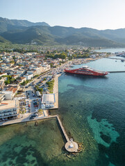 Fototapeta premium Thasos Town Waterfront with Red Ferry and Mountain Background