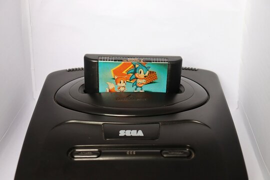 Salvador, Brazil - July 11, 2026. Sega Mega Drive console and Sonic The Hedgehog game on white background. Vintage video game. 