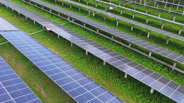 Aerial view along long rows of solar panels and grass