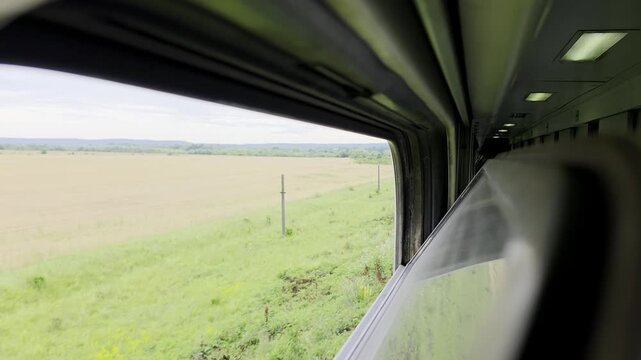 POV train window view of passing fields and horizon.