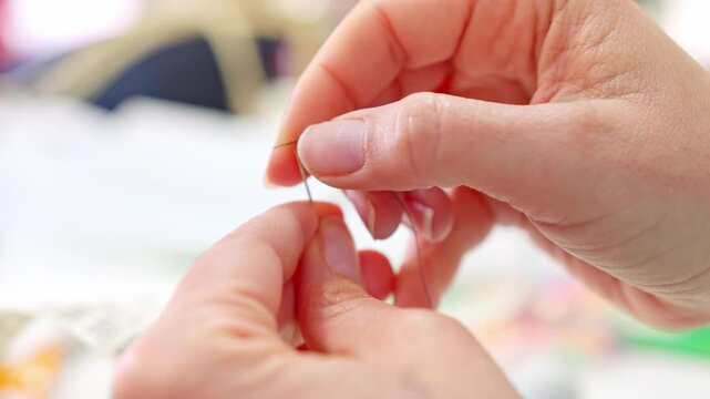 Tailor hands threading a needle in a workshop