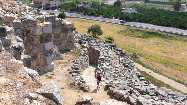 Female traveler exploring ancient Tiryns acropolis ruins in Greece
