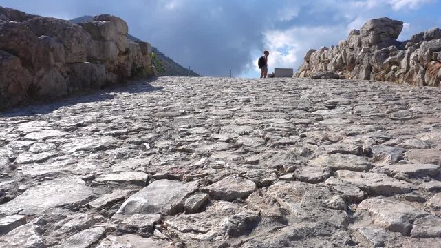 Hiker walking up an ancient cobblestone road in Mycenae