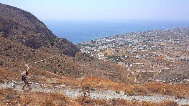 Hiker walking down a mountain trail in Santorini, Greece