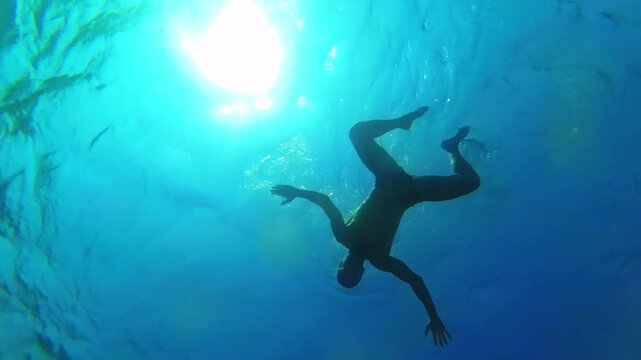 Man swimming and doing a somersault underwater