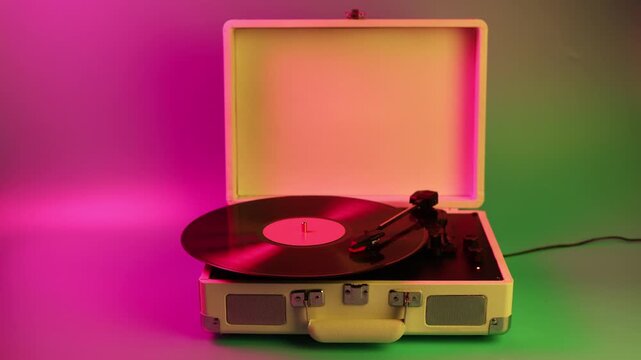 Retro portable record player with vinyl spinning in colorful neon lighting