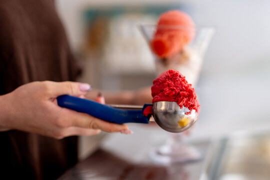 Hand scoops bright red ice cream dessert