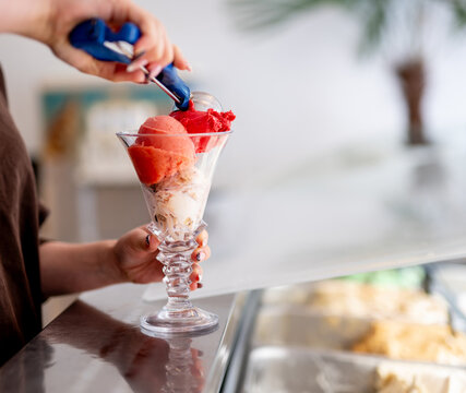 Scooping vibrant ice cream into elegant sundae glass