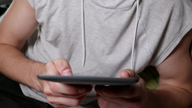 A close-up shows a man's hands holding an electronic book reader indoors, emphasizing digital reading and modern education. This image captures the convenience of technological advancements in