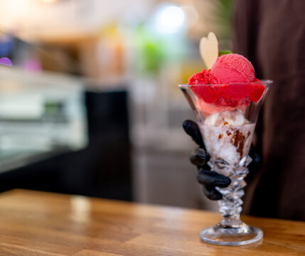 Hand serving strawberry vanilla ice cream parfait