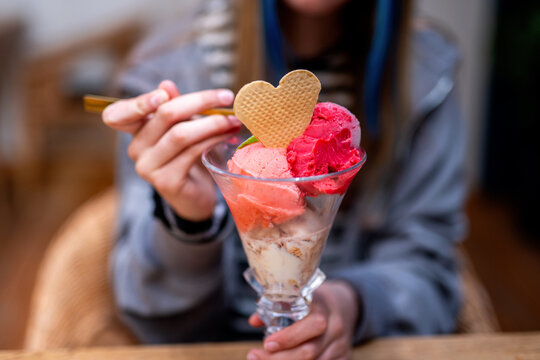 Child eats ice cream sundae with heart waffle cookie