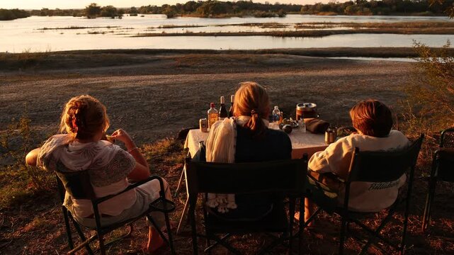traveling family enjoying "sundowners" at sunset on the banks of the Zambezi River, Zimbabwe, Africa