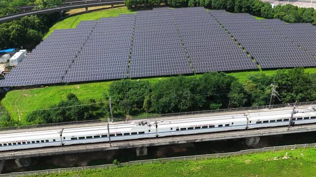 High-speed train passing photovoltaic solar farm from aerial view