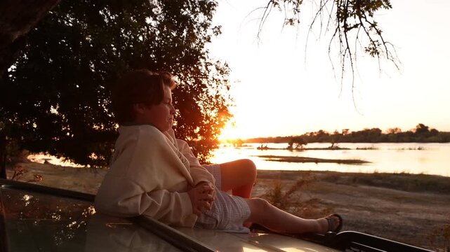 traveling family enjoying "sundowners" at sunset on the banks of the Zambezi River, Zimbabwe, Africa
