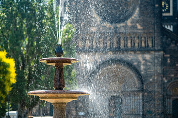 Naklejka premium Fountain in Prague with water spraying near a historic building during daytime