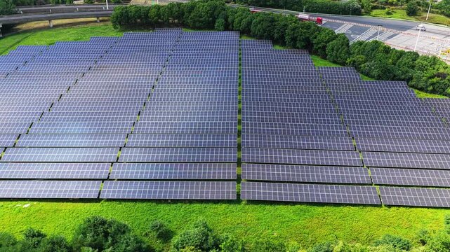 Wide aerial view of large solar power plant and trees