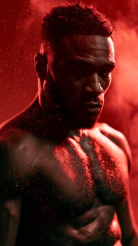 Intense portrait of a muscular Black man with sweat and red lighting